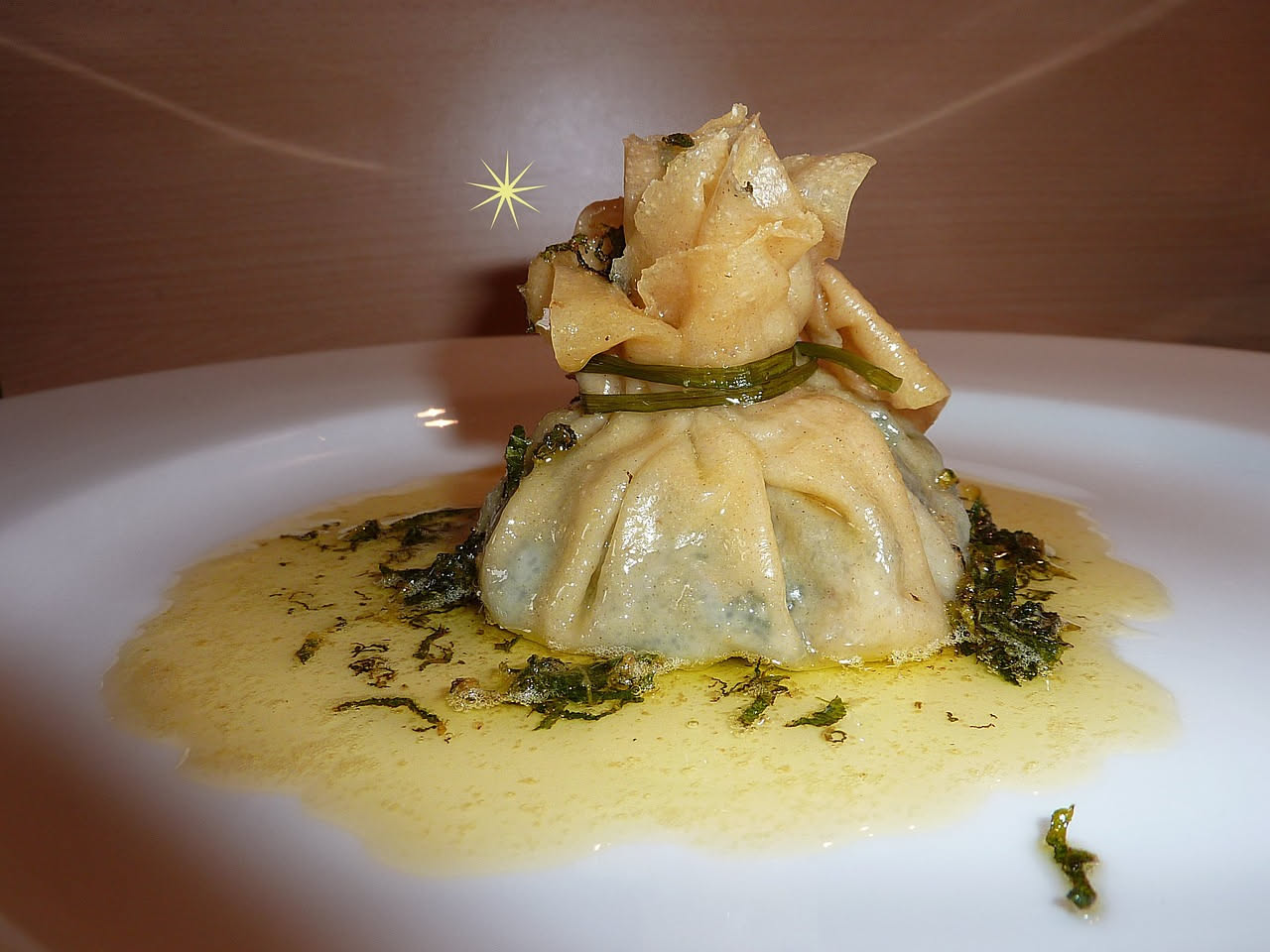 Condiglione ligure servita in ciotola bianca: cubetti di pane tostato, pomodori rossi, cetrioli verdi, olive nere, acciughe filettate, il tutto bagnato da olio d'oliva trasparente e condito con prezze