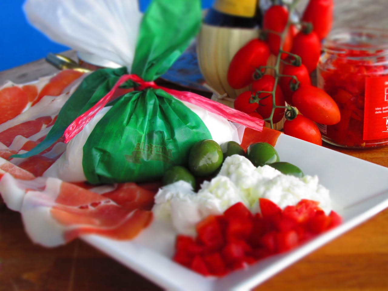 Burrata tagliata a metà su un piatto bianco, con la stracciatella cremosa che fuoriesce, circondata da pomodori ciliegini rossi e basil fresco verde
