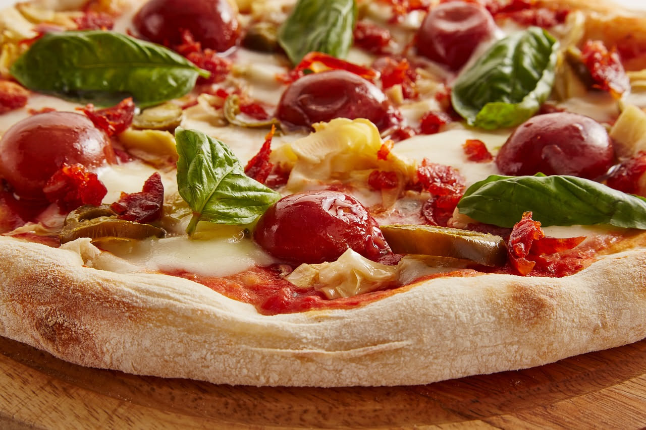 Nduja calabrese affettata su un tagliere di legno, con il caratteristico colore rosso acceso dovuto al peperoncino, accanto a pane toscano tostato