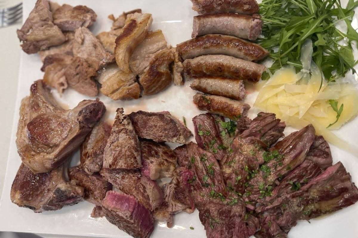 Tavolo di legno con diversi tagli di carne rossa: bistecca, costata, filetto, spalla e carne macinata, distribuiti su carta da macelleria bianca