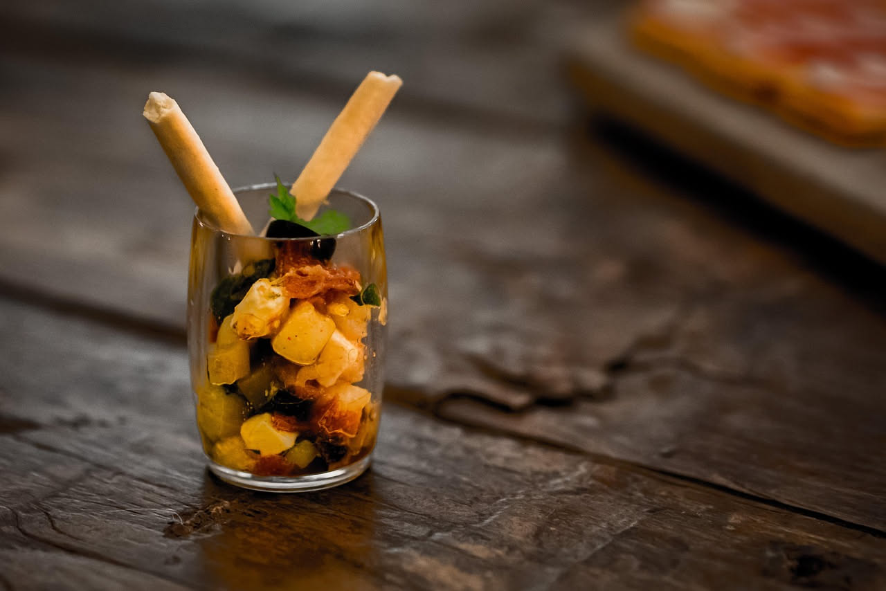 Panzanella toscana servita in piatto bianco: cubetti di pane dorato mescolati a pomodori rossi, cipolla bianca, basilico verde e olio d'oliva; insalata umida e colorata con gocce d'olio visibili
