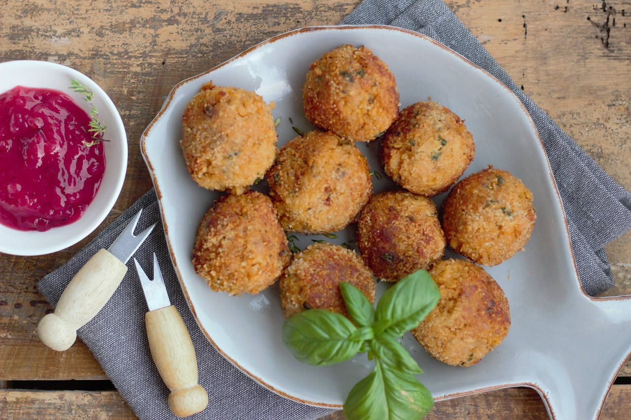 Polpette di tonno dorate e rotonde disposte su un piatto bianco, con una leggera doratura croccante, accompagnate da limone fresco tagliato a fette e qualche foglia di prezzemolo verde