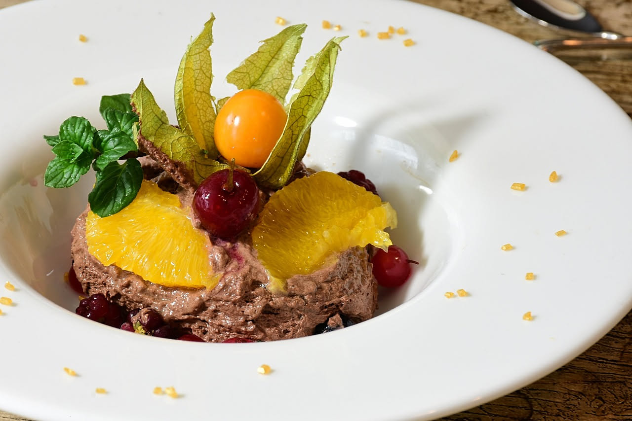 Insalata bianca e arancione in piatto largo e bianco, con finocchi tagliati sottilissimi, spicchi di arancia fresca, foglie di finocchio verde e condimento limpido di olio.