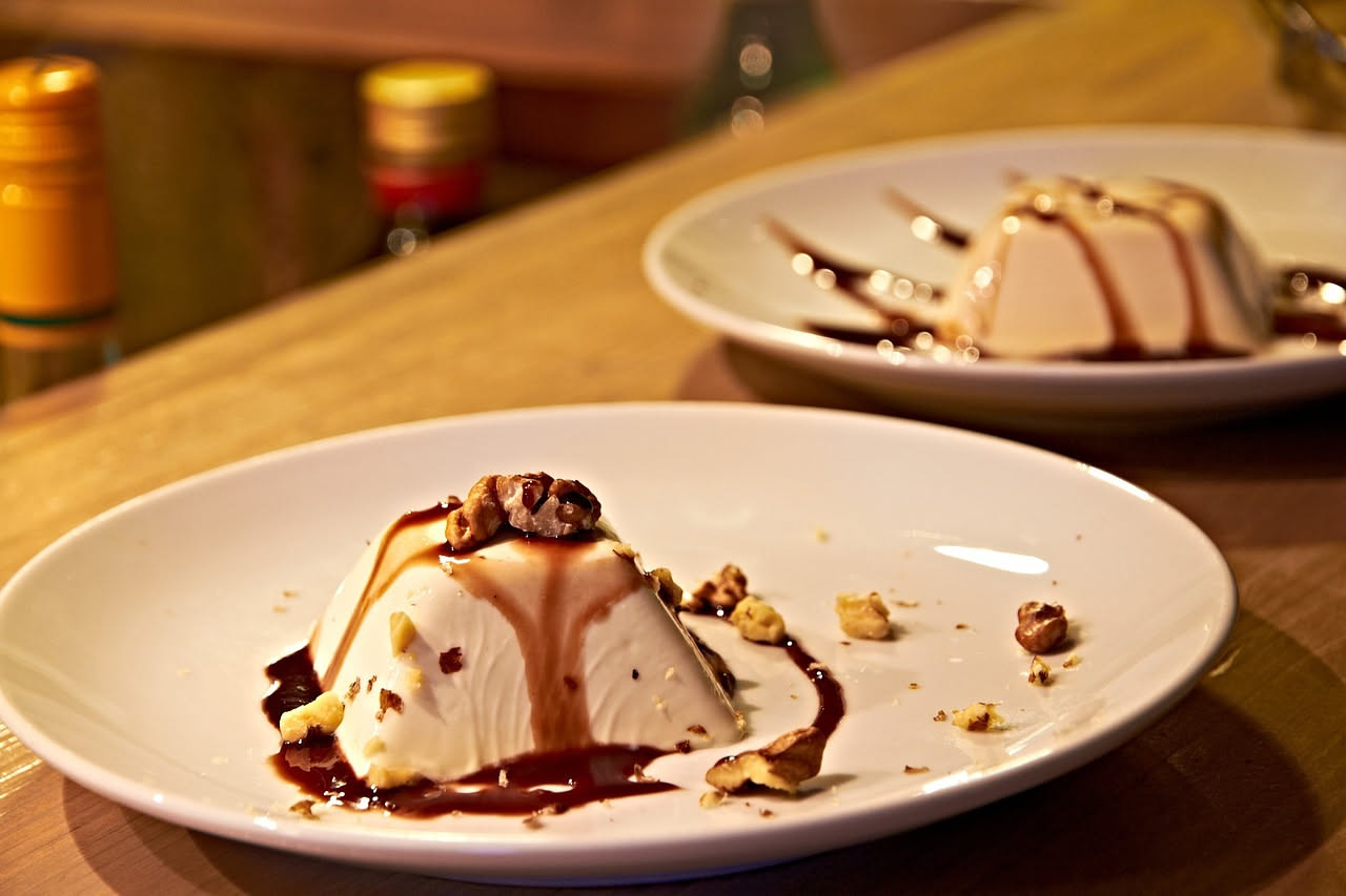 Semifreddo al limone affettato in piatti bianchi, con crema gialla pallido, guarnito da scorza di limone e foglia di menta, sfondo bianco