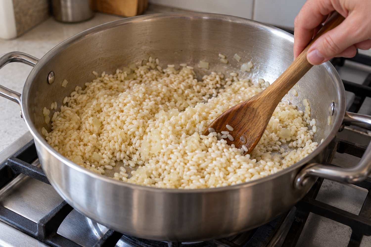 Cucchiaio di legno che mescola riso a chicco corto con cipolla tritata e olio in una casseruola