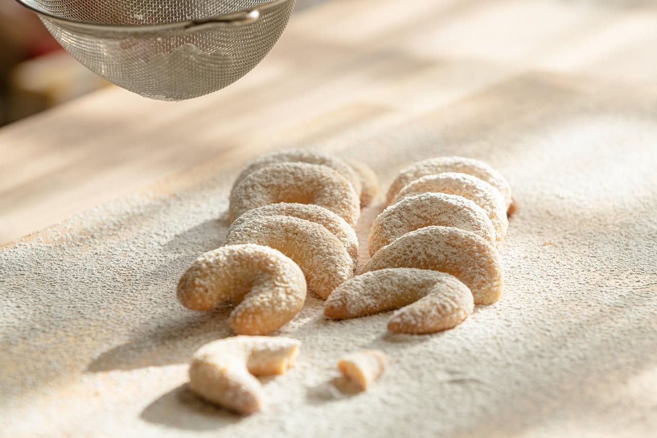 Crescentine modenesi dorate e gonfie in un piatto bianco, accompagnate da mortadella affettata e uno spicchio di aceto balsamico di Modena
