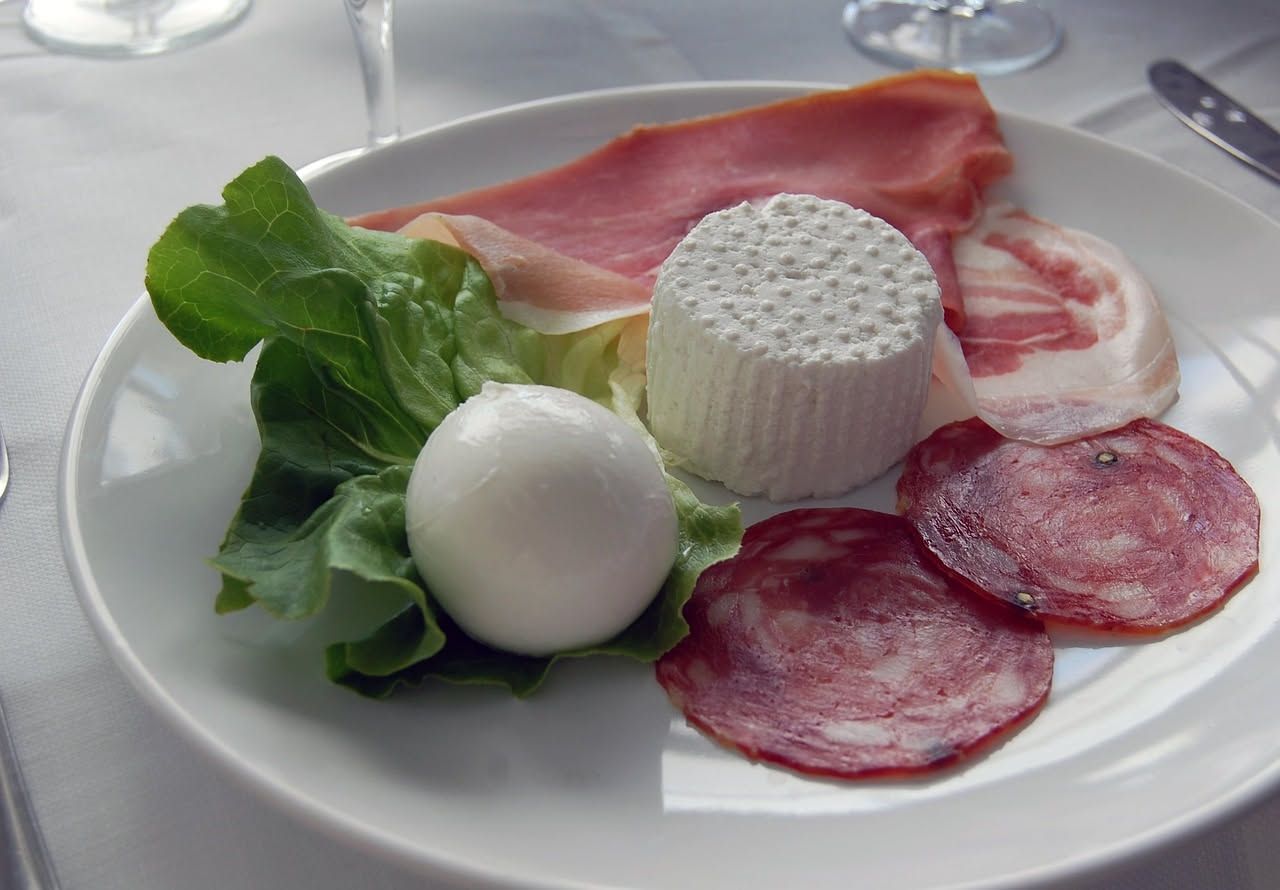 Gnocco fritto aperto che mostra il ripieno di prosciutto, mortadella e formaggio, piatto su carta da forno con superficie dorata e croccante