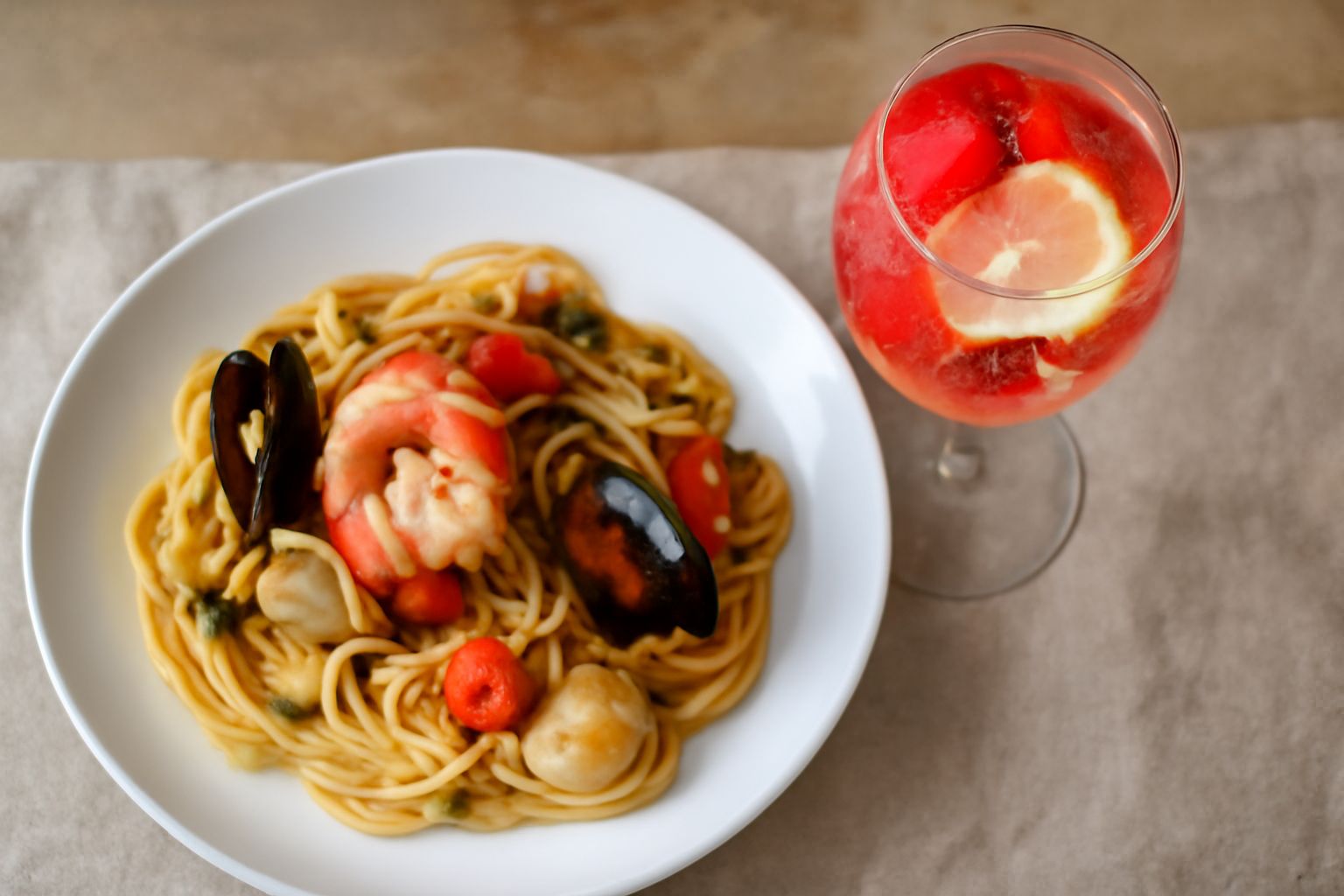 Bicchieri trasparenti di Golfo dei Poeti rosato con sfumature rosa pallido, decorati con fragole fresche e fettine di limone galleggianti, circondati da cubetti di ghiaccio e foglie di menta, su un ta