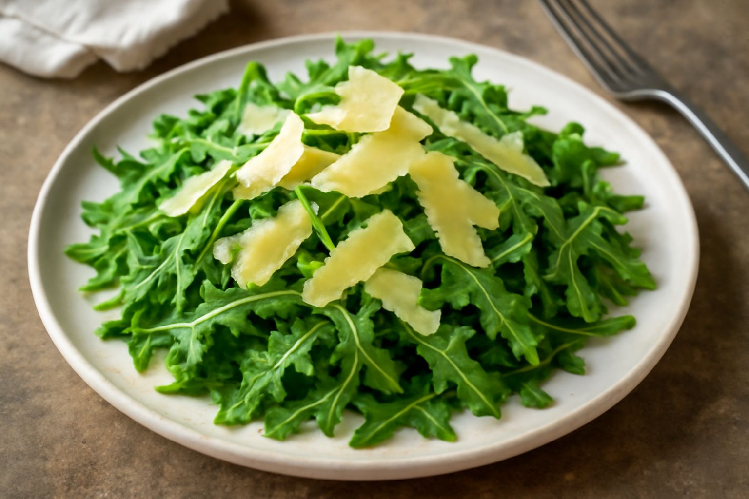 Insalata in una ciotola bianca: rucola verde scuro e croccante, scaglie dorate di grana parmigiano sparse sopra, filo di olio d'oliva che cade, limone tagliato mezzo sullo sfondo