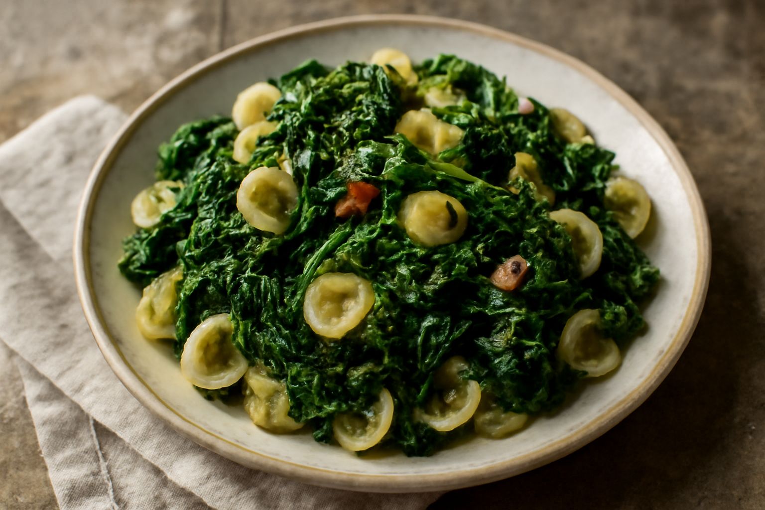Orecchiette verdi e bianche condite con cime di rapa scure, aglio dorato e olio d'oliva lucente, servite in un piatto bianco fondo con una spruzzata di peperoncino rosso acceso