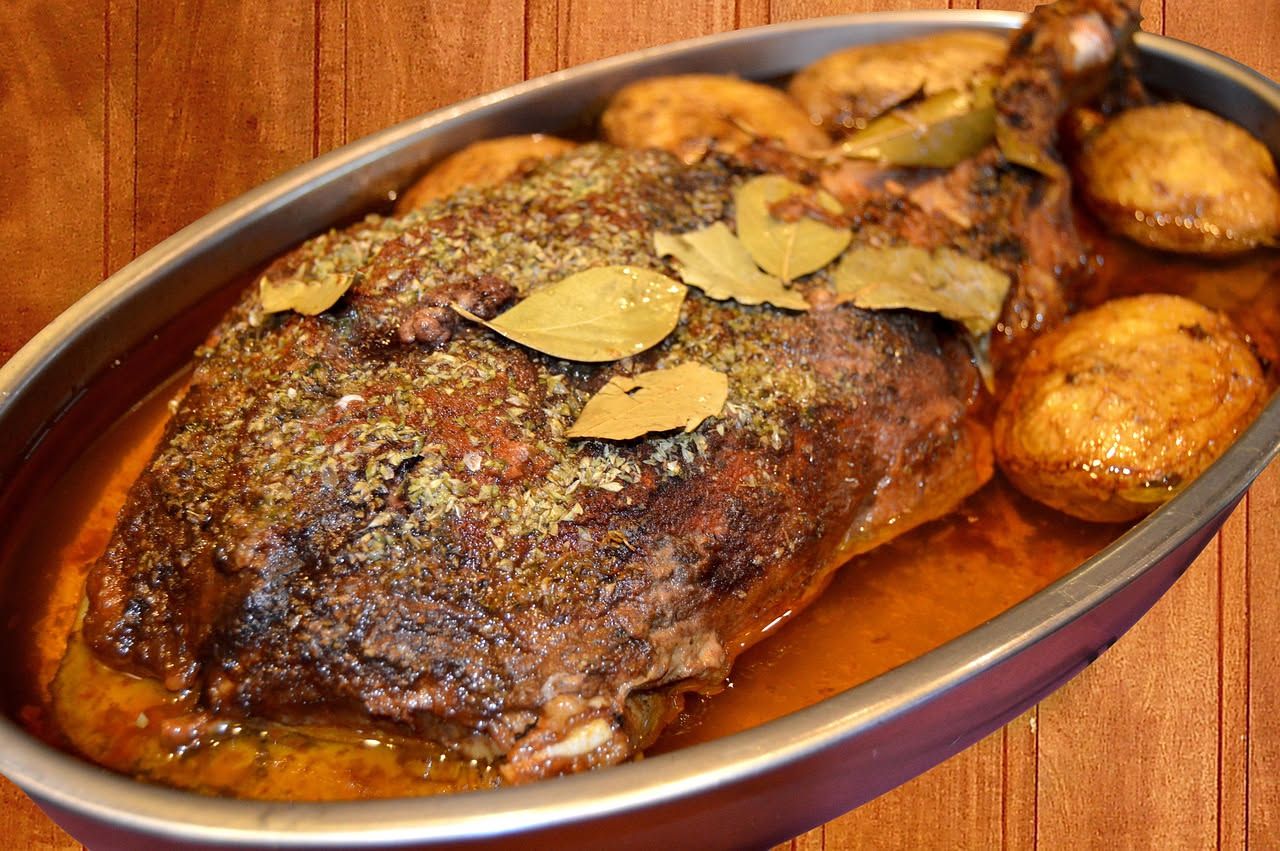 Ossocollo di manzo rosso scuro affettato in un piatto bianco con brodo caldo e verdure di contorno leggermente appassite, vapore visibile
