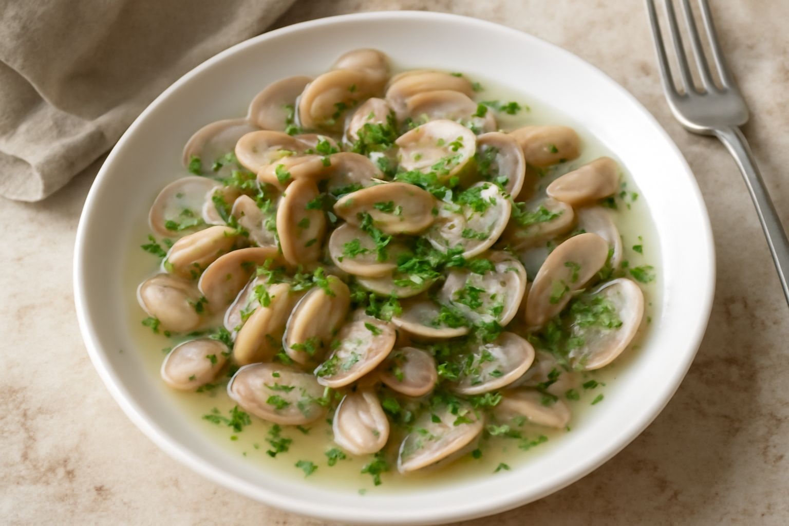 Piatto bianco con telline aperte che rivelano la polpa color crema, brodo di cottura trasparente con tracce di prezzemolo fresco e aglio, accompagnate da una fetta di pane tostato sul bordo