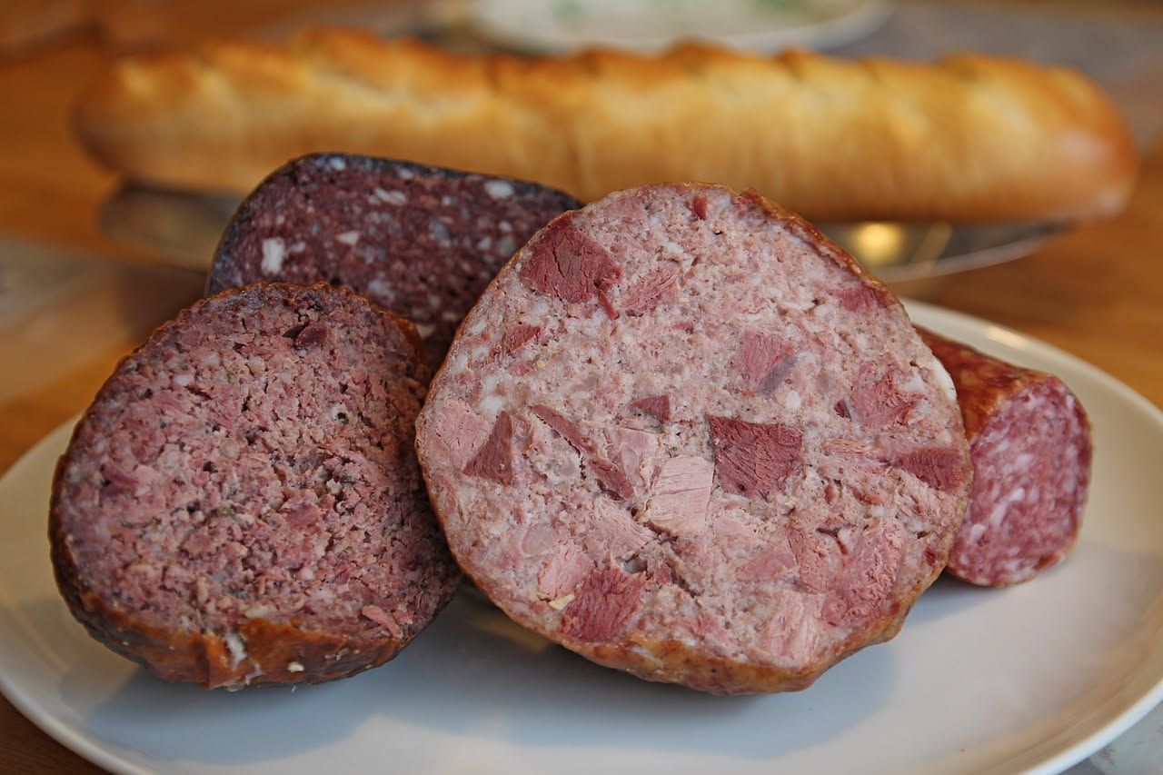 Zampone Modena cotto affettato su un piatto bianco, servito con lenticchie e contorno di verdure di stagione, in una ambientazione di cucina tradizionale